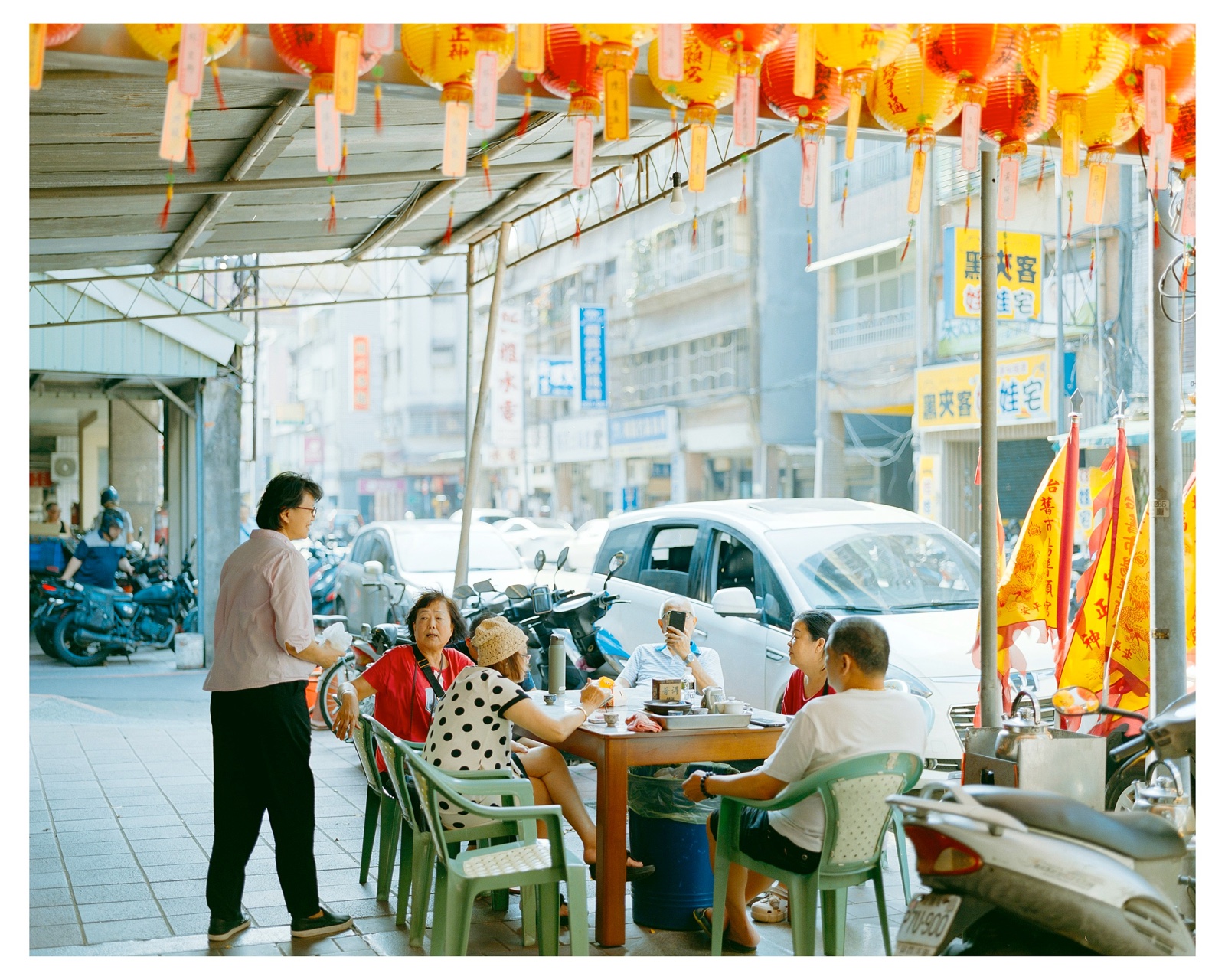红黄灯笼下，几个人围坐在街边的桌旁喝茶聊天